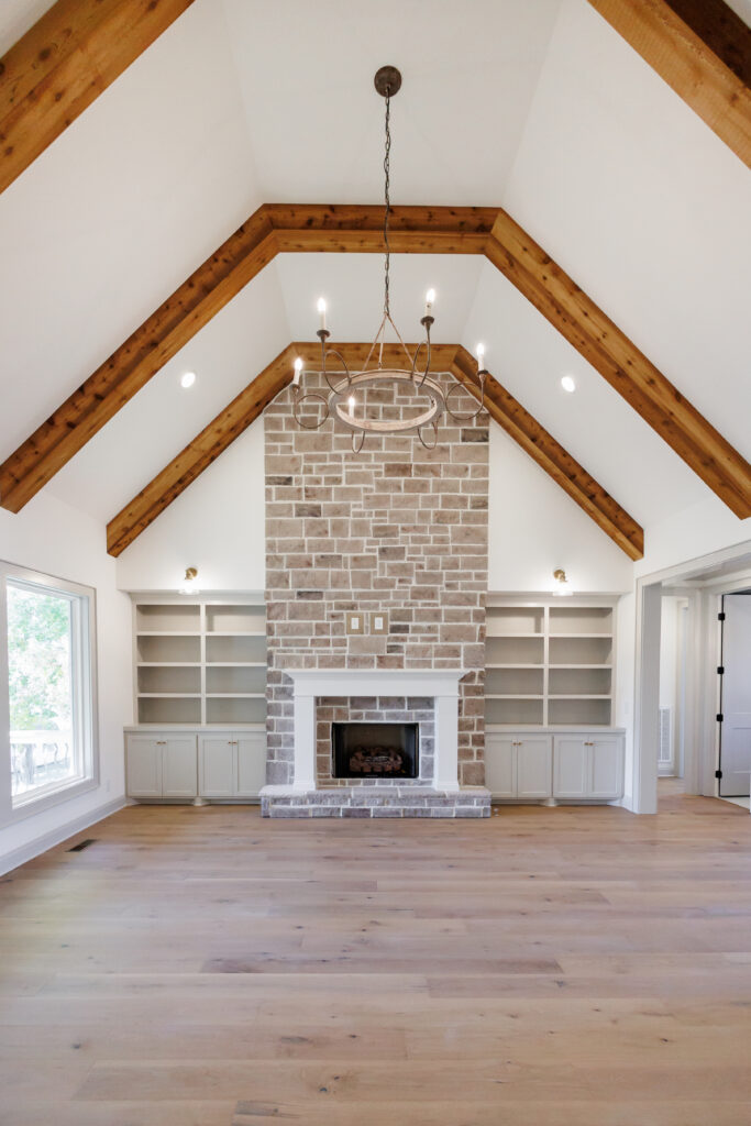 Vaulted living room with exposed wood beams and a stone fireplace
