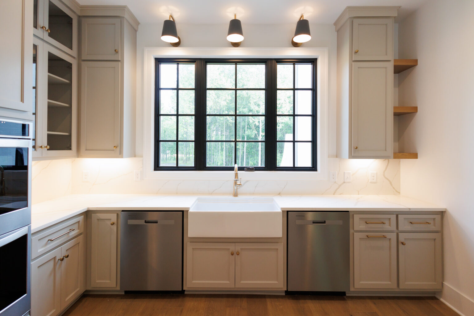 Kitchen with a farmhouse sink under black-framed windows and warm gray cabinetry
