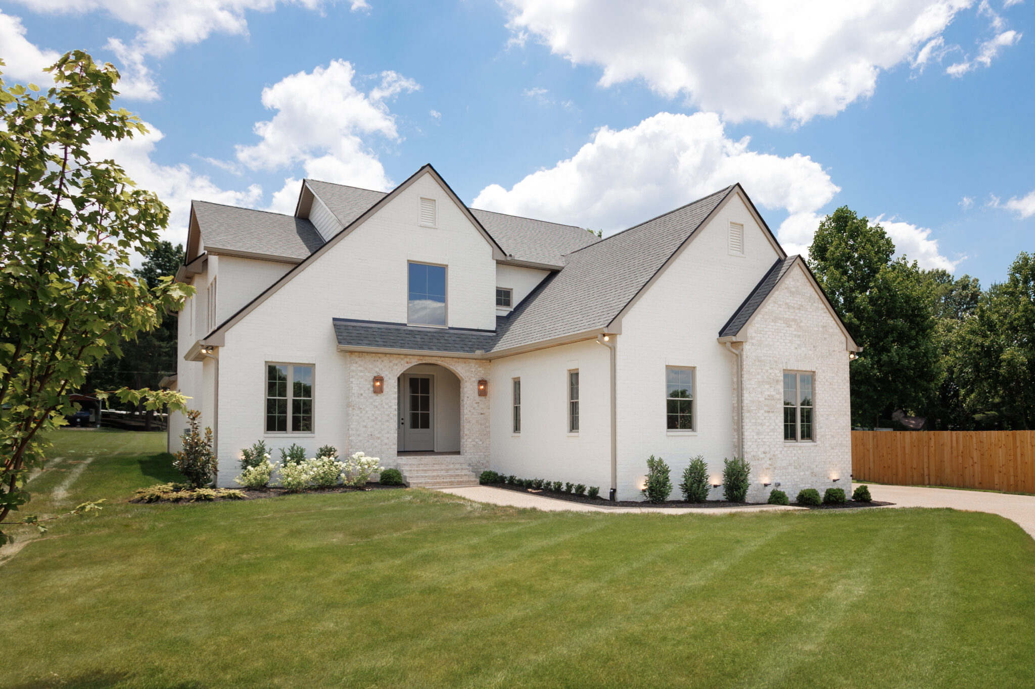 White brick two-story home with a gabled roof and landscaped lawn, built by Stewart Knowles Construction