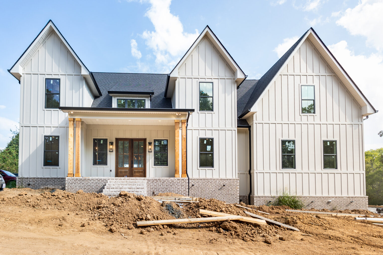 New white board-and-batten farmhouse under construction on its homesite